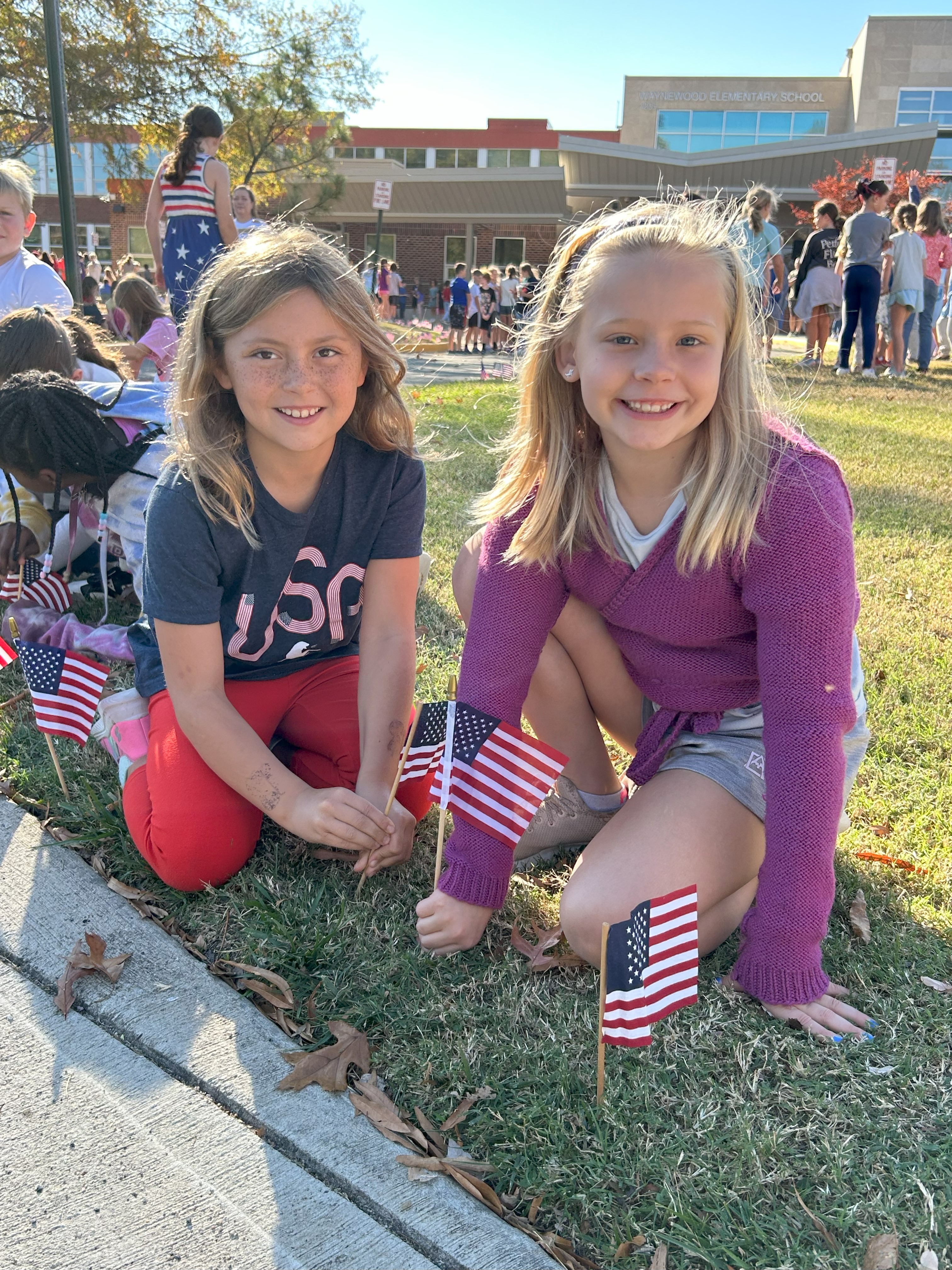 students posting the United States of America flag in front of the school