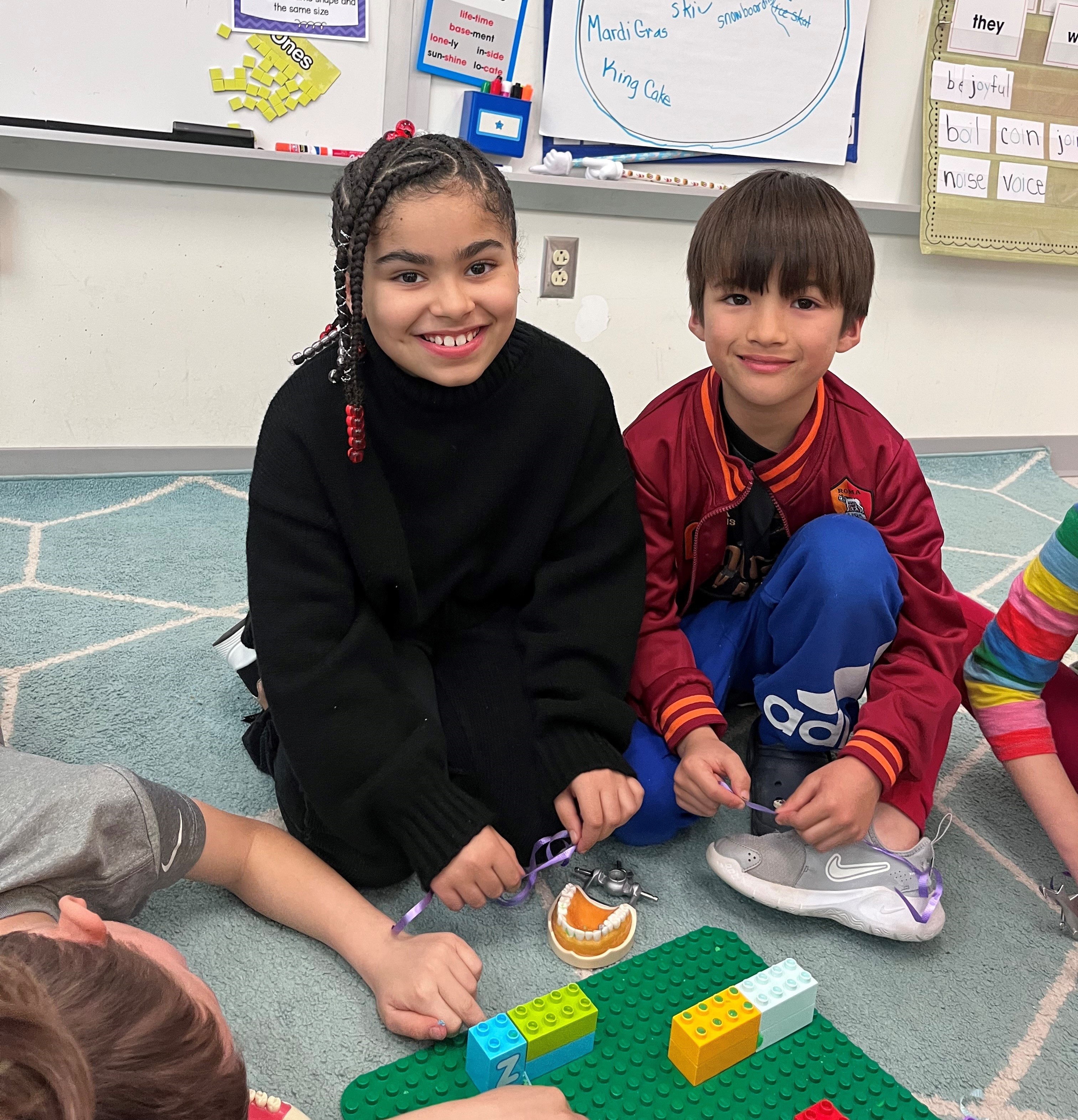 Students using rubber bands on plastic blocks to learn about flossing.