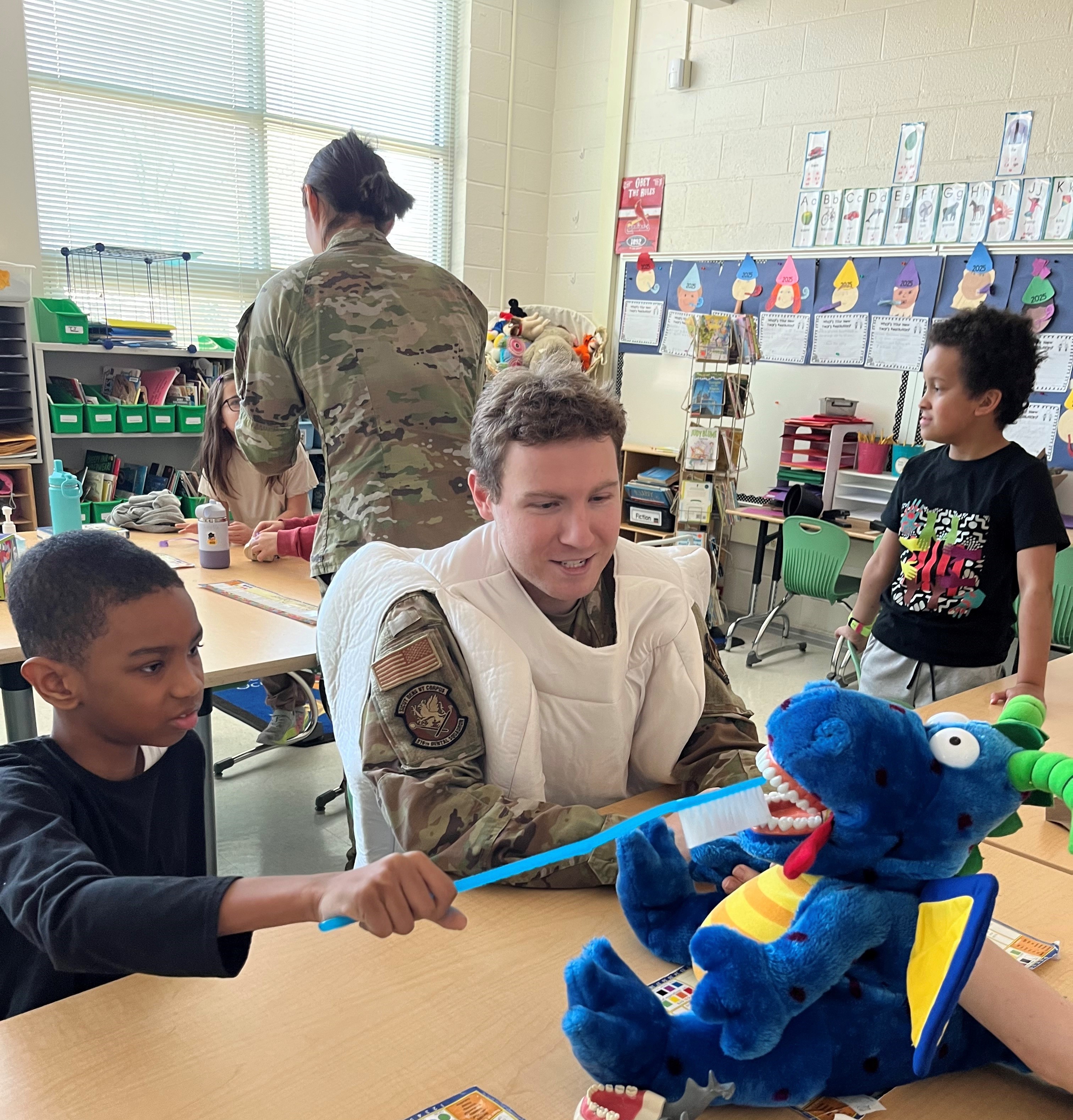 Student brushing the teeth of a stuffed animal with the assistance of a dental student.  