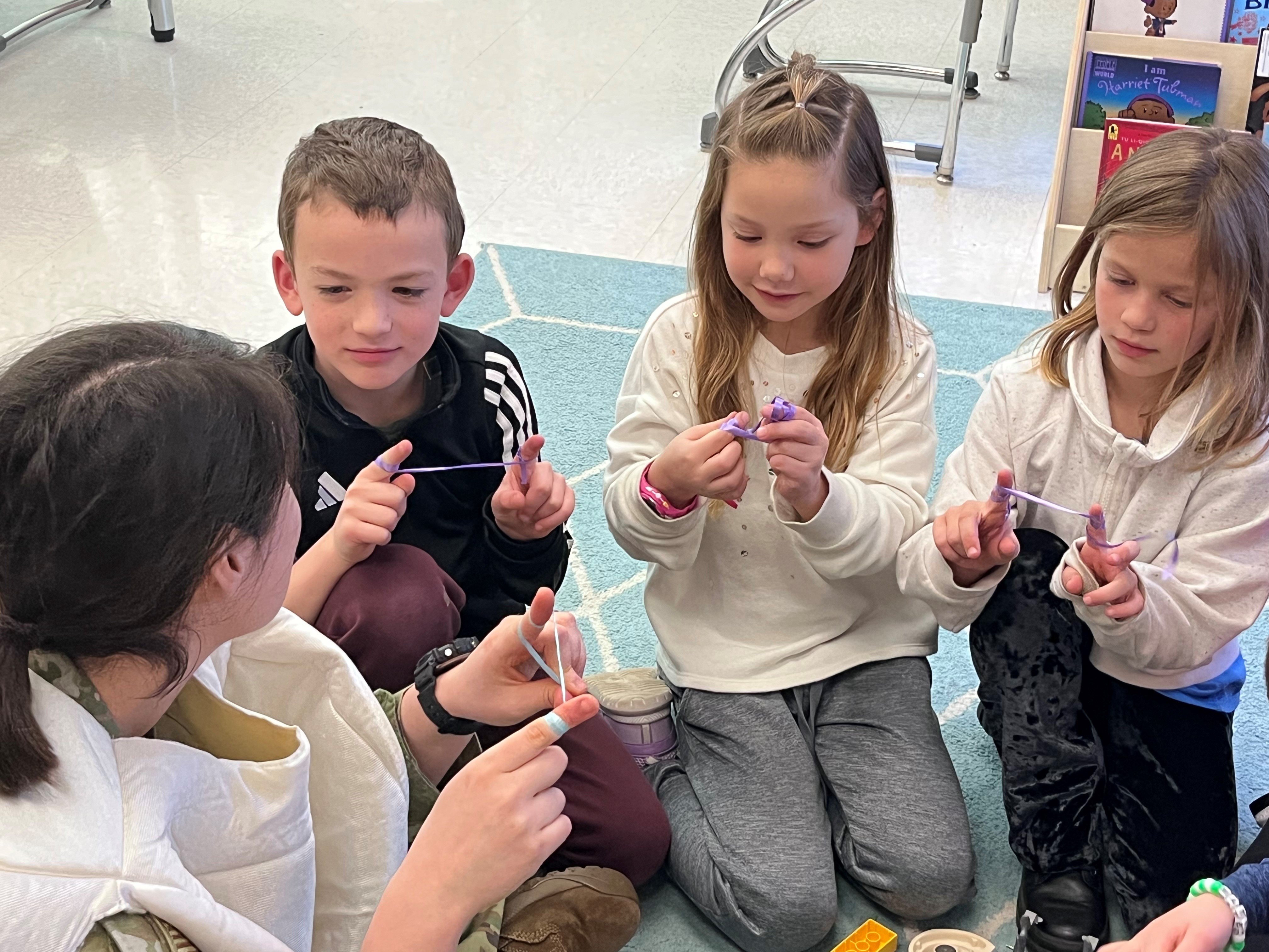 Students sitting on the floor practing using dental floss.